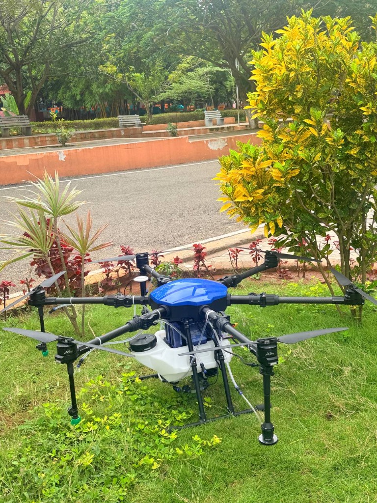 Agricultural drone spraying crops at dusk with green status lights